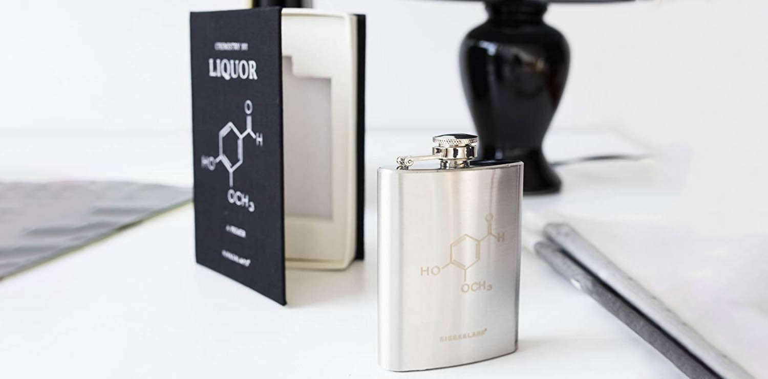 Product image of a flask with the chemical symbol for liquor on it, in front of a fake book that holds it.